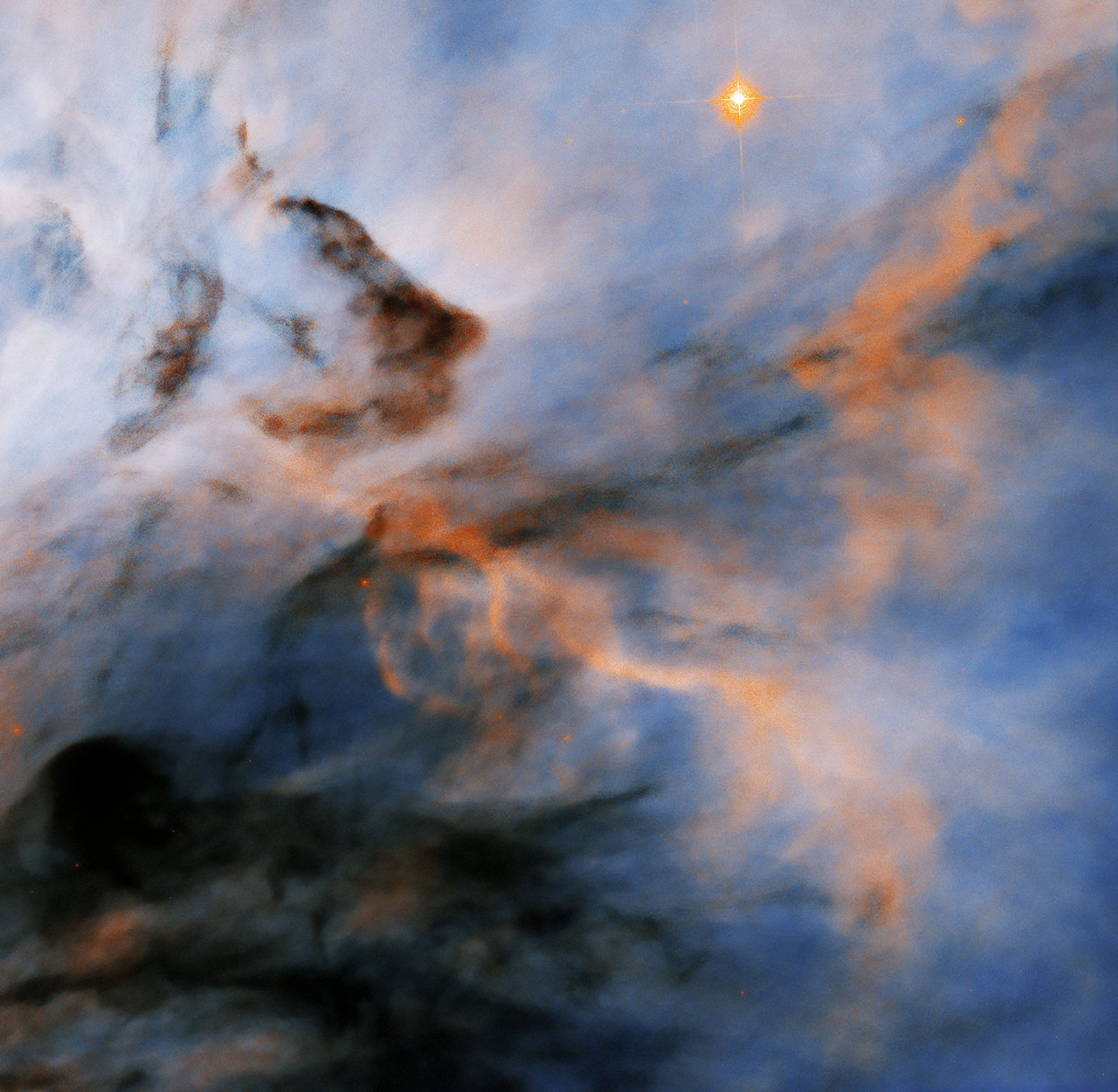 Hubble image of blue and white background cloud superimposed with orange and dark cloudy wisps.